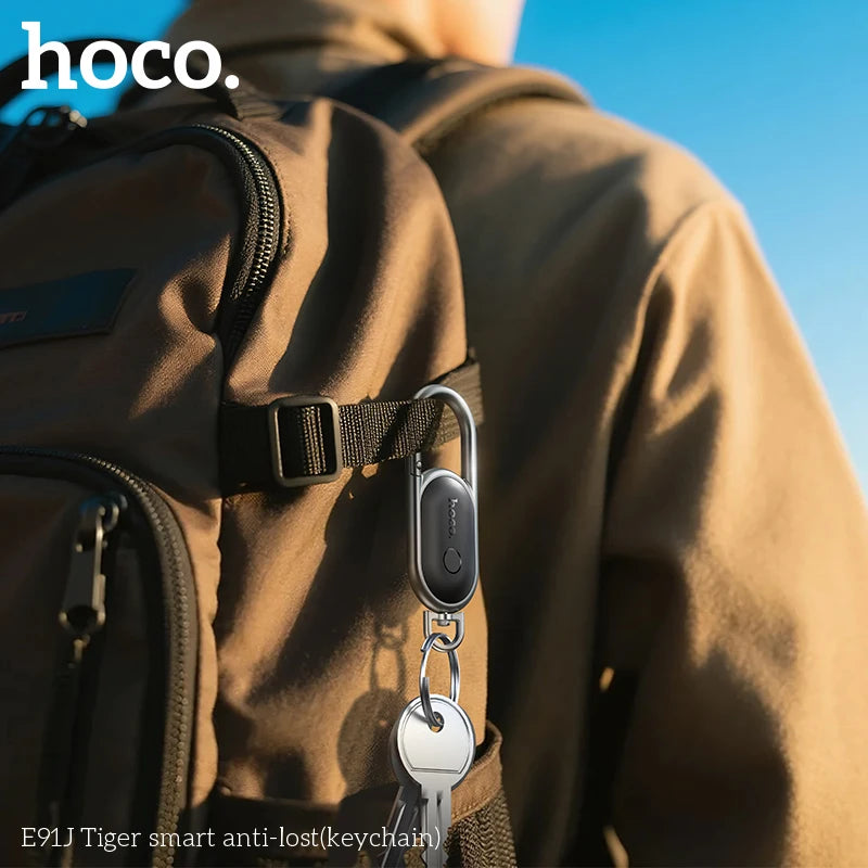Person wearing a backpack with a smart anti-lost keychain attached, featuring the brand 'hoco'.