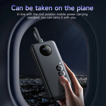Hand holding a power bank with an airplane window in the background
