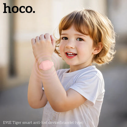 Child holding a smartphone with 'hoco.' branding, standing outdoors.