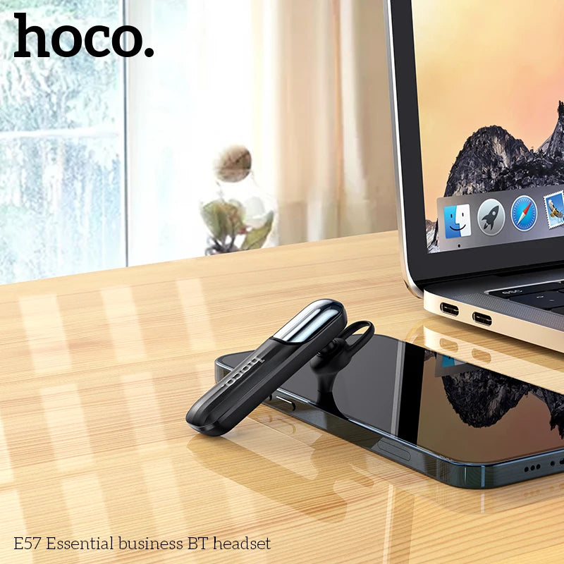 Hoco E57 Essential business BT headset on a desk with a laptop in the background